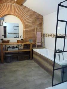 uma casa de banho com uma banheira, uma mesa e um lavatório. em La cave 1874 , logement atypique em Saint-Jean-Lasseille
