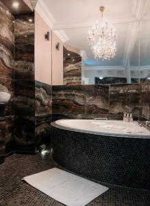 a bathroom with a bath tub and a chandelier at Coral Tree Inn in Pretoria