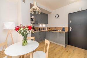 una cucina con tavolo bianco e vaso di fiori di Apartament 128 KOŁO BRZEGU, SPA, PARKING Kołobrzeg Podczele Lwowska a Kołobrzeg