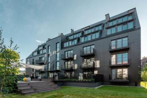 un edificio nero con un prato davanti di Apartament 128 KOŁO BRZEGU, SPA, PARKING Kołobrzeg Podczele Lwowska a Kołobrzeg