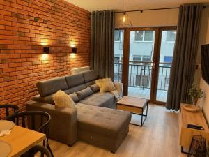 a living room with a couch and a brick wall at Apartament Silence Karpatia Resort Koral in Karpacz