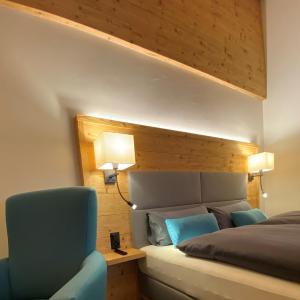a bedroom with a bed and a blue chair at Adults Only Hotel Mulin - Das Erwachsenen-Hotel in den Bergen in Breil/Brigels