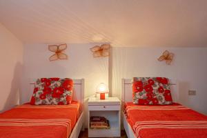 a bedroom with two beds with red sheets and a lamp at coda cavallo villaggio cala paradiso villino C4 in San Teodoro +19 photos