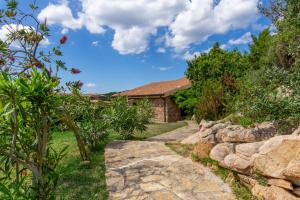 un giardino con sentiero in pietra che conduce a una casa di coda cavallo villaggio cala paradiso villino C4 a San Teodoro
