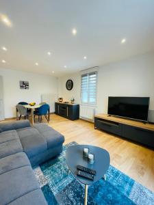 sala de estar con sofá, TV y mesa en Appartement Les Tilleuls "3 étoiles", en Niederbronn-les-Bains