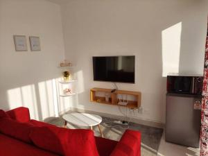 a living room with a red couch and a tv at Stylish Studio on Ngong Road in Nairobi