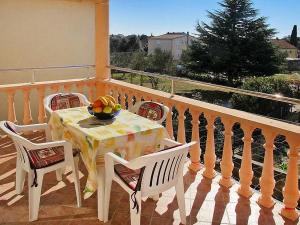 einen Tisch mit Stühlen und eine Obstschale auf dem Balkon in der Unterkunft Nives apartmani in Pakoštane