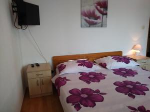 ein Schlafzimmer mit einem Bett mit lila Blumen darauf in der Unterkunft Nives apartmani in Pakoštane