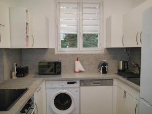 a kitchen with a washing machine and a microwave at Spacieux F5 au parc arboré in Orsay