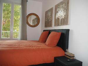 una camera da letto con letto, cuscini arancioni e specchio di Spacieux F5 au parc arboré a Orsay