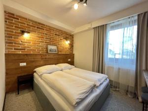 a bedroom with a bed and a brick wall at Pensjonat Winnica in Toruń