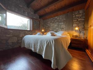 Un dormitorio con una cama y una pared de piedra. en El Vilarot. La casa de piedra en la naturaleza., en Girona