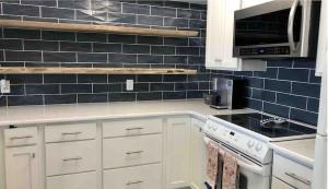 a kitchen with white cabinets and blue tiles on the wall at Newly Renovated Beach Condo with STUNNING Water Views! Monthly and Weekly Specials! in Carolina Beach +9 photos