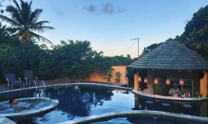 a swimming pool with a gazebo next to a house at Pousada Oceano in Caraíva