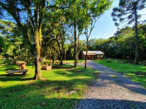 un camino en un parque con un banco y un edificio en Sitio Recanto Feliz, en Gramado