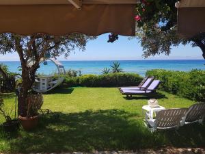 a yard with two chairs and a swing and the ocean at Corfu Dream Holidays Villas in Glyfada