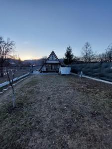 uma casa com uma árvore em frente a um quintal em Cabana La Bica em Măgureni