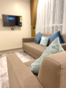 sala de estar con sofá y TV en Alhamra Horizons, en Al Ḩamrāʼ
