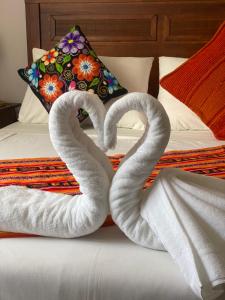 dos cisnes de toalla sentados en la parte superior de una cama en Refugio del Maipo Lodge, en San José de Maipo