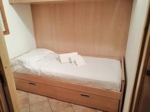 uma cama num pequeno quarto com lençóis brancos e almofadas em Apartment "Casa Maya" em Mezzana