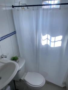 Baño blanco con aseo y lavamanos en Apartamento Ucha, en Ríohacha