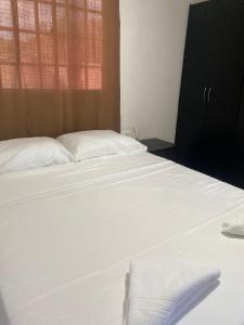 1 dormitorio con 2 camas con sábanas blancas y ventana en Apartamento Ucha, en Ríohacha
