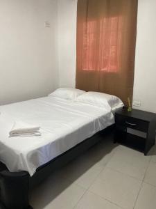Schlafzimmer mit einem Bett mit weißer Bettwäsche und einem Fenster in der Unterkunft Apartamento Ucha in Ríohacha