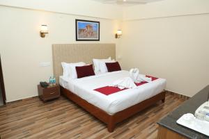 una camera da letto con un grande letto bianco con cuscini rossi di Gadiraju Palace Convention Centre & Hotel a Visakhapatnam