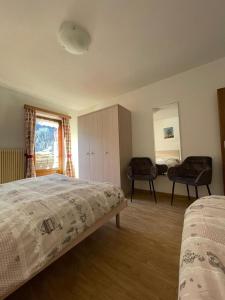 a bedroom with a bed and two chairs in it at Cèsa Soracrepa in Canazei