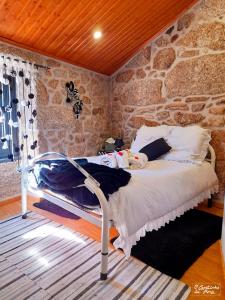 
a white bed sitting in a room next to a wall at O Cantinho da Ana in Sortelha
