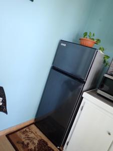 a black refrigerator in a kitchen with a blue wall at Urban Oasis Apartment in Castries