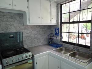 a kitchen with white cabinets and a sink and a stove at Urban Oasis Apartment in Castries