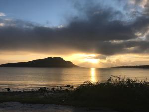 a sunset over a body of water with a mountain at Monawilline Cottage in Lamlash