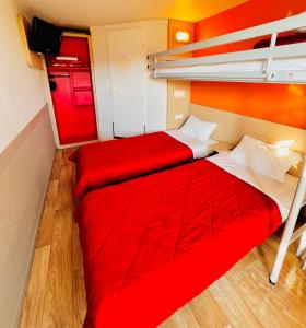 a bedroom with two beds and a red blanket at Premiere Classe St Quentin en Yvelines Elancourt in Trappes