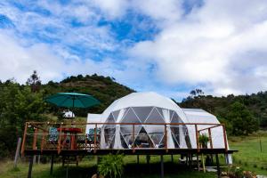 a large dome tent with an umbrella on a deck at Glamping Claro de Luna in Guatavita
