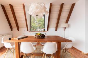 a dining room with a wooden table and white chairs at Vista Mountain House in Kopaonik