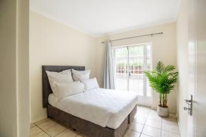 a bedroom with a bed with white sheets and a plant at Beautiful Two Bedroom Appartment In Hatfield in Pretoria