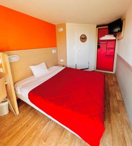 a bedroom with a large bed with a red blanket at Premiere Classe St Quentin en Yvelines Elancourt in Trappes