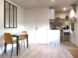 a kitchen and dining room with a table and yellow chairs at Studio ALYA, mini-gîte en campagne de Lizio in Lizio