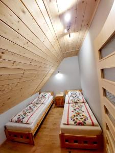 two beds in a room with a wooden ceiling at Domki w Beskidach in Zarzecze
