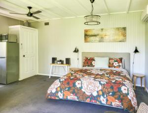 a bedroom with a bed with a floral bedspread and a refrigerator at Aurora Cottage in Hepburn Springs