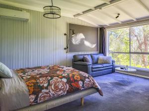1 dormitorio con cama, sofá y ventana en Aurora Cottage en Hepburn Springs