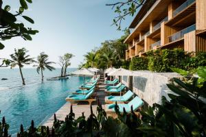una piscina en el complejo con tumbonas y sombrillas en Cape Dara Resort - SHA Plus en Pattaya North