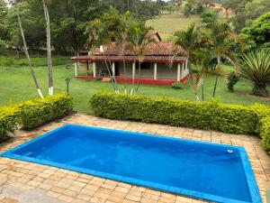 a blue swimming pool in front of a house at CHACARA SANTA RITA in Extrema