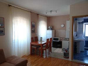 ein Wohnzimmer mit einem Tisch und einer Küche in der Unterkunft Apartment Pavešić 1 in Mali Lošinj