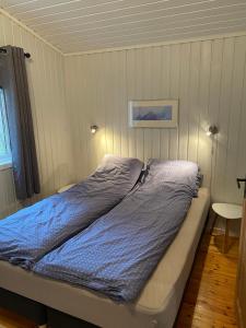 uma cama com um edredão azul num quarto em Waterfront mountain view cabin Lofoten em Liland