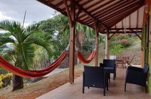 a hammock on a patio with a table and chairs at La Villa Terracotta - Vue mer panoramique in Le Diamant