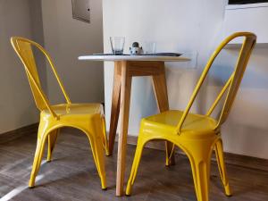 查克拉斯德科里亞的住宿－Moderno departamento para dos personas en Chacras de Coria，两张黄色椅子,旁边是一张桌子,桌子上是黄色桌子