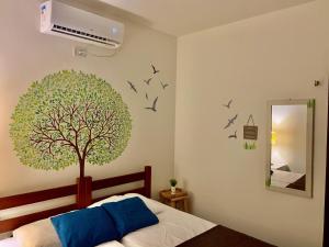 a bedroom with a tree and birds on the wall at Chalés Sossego da Serra in Serra de São Bento