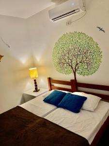 a bedroom with a bed with a tree on the wall at Chalés Sossego da Serra in Serra de São Bento